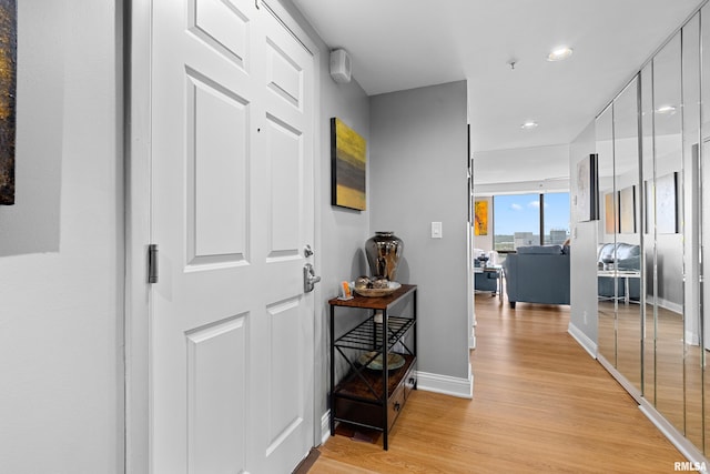 hall with baseboards, recessed lighting, and light wood-style floors