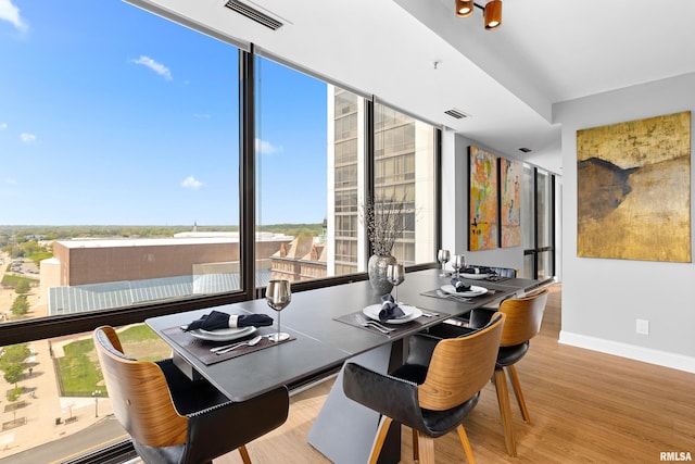 dining area with baseboards, visible vents, and wood finished floors