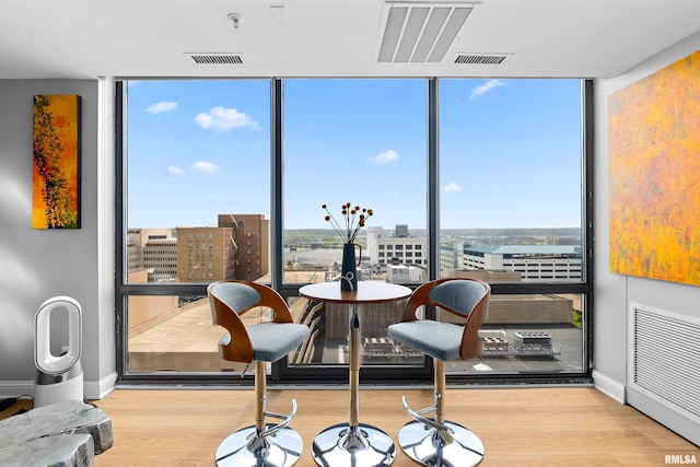 dining area with a wall of windows, a city view, and wood finished floors