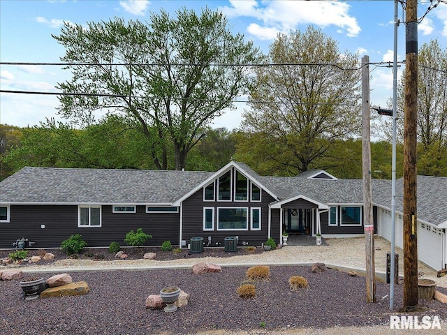 view of front of home featuring central AC unit, a shingled roof, and an attached garage