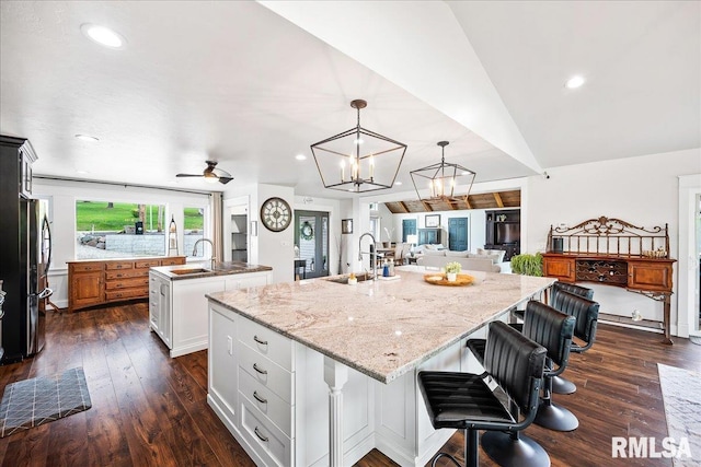 kitchen featuring freestanding refrigerator, dark wood finished floors, a large island with sink, and a sink