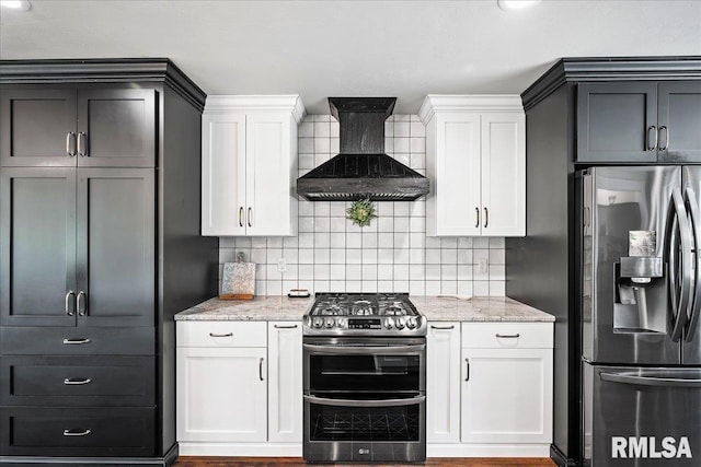 kitchen with light stone countertops, backsplash, wall chimney range hood, and stainless steel appliances