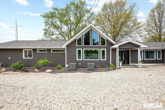rear view of property with central AC unit and roof with shingles