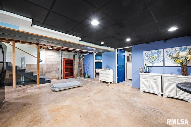 unfinished below grade area with recessed lighting, concrete block wall, and stairway