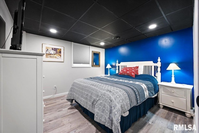 bedroom with baseboards, visible vents, a drop ceiling, and wood finished floors