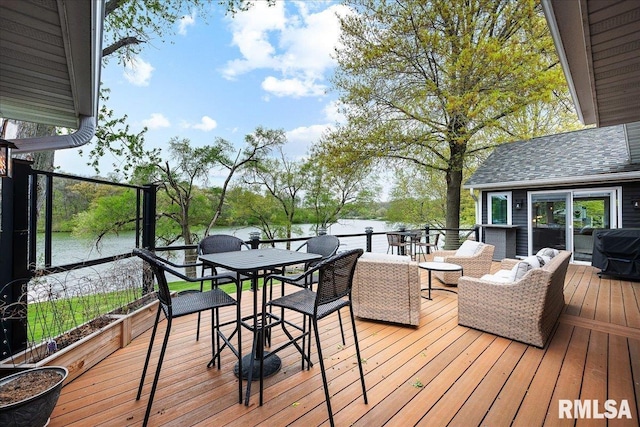 wooden terrace featuring outdoor dining space and a water view