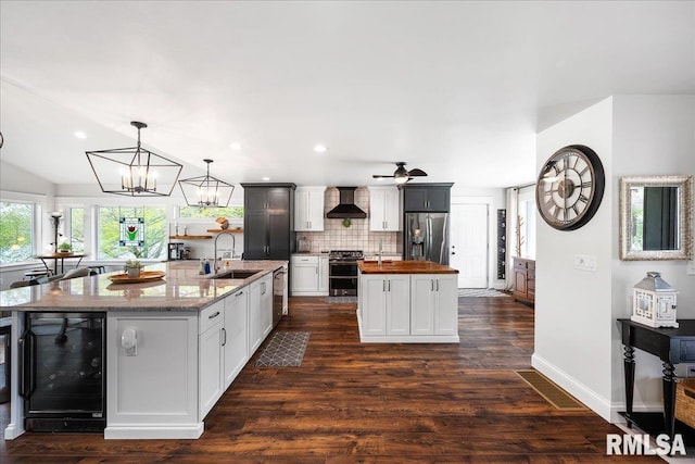 kitchen featuring a kitchen island with sink, wooden counters, a sink, wine cooler, and stainless steel appliances