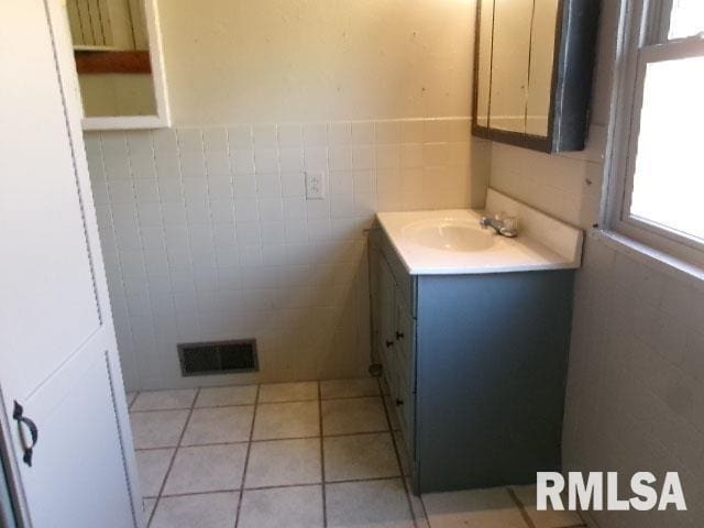 bathroom with visible vents, a wainscoted wall, tile walls, tile patterned floors, and vanity