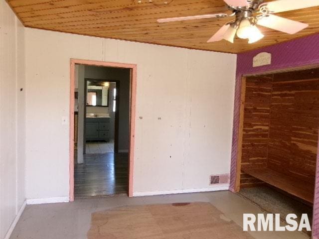 unfurnished bedroom featuring baseboards, wooden ceiling, ceiling fan, and a closet
