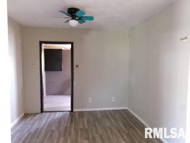 unfurnished room with wood finished floors, a ceiling fan, and baseboards