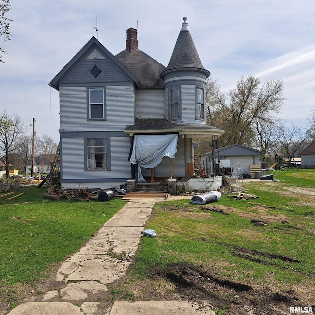 rear view of house with a porch, a garage, a lawn, and a chimney