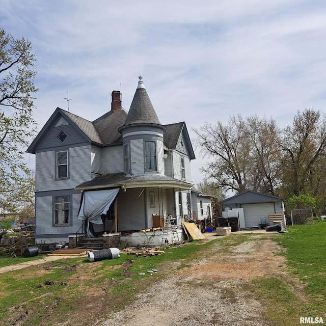victorian home featuring a garage, covered porch, a chimney, and a front lawn