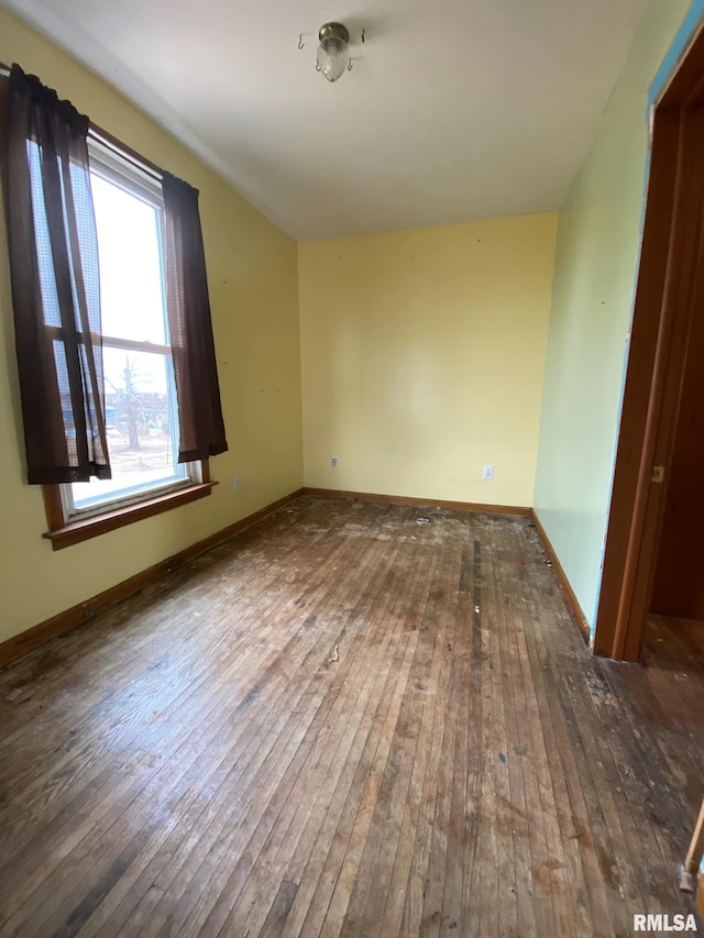 spare room with baseboards and hardwood / wood-style flooring