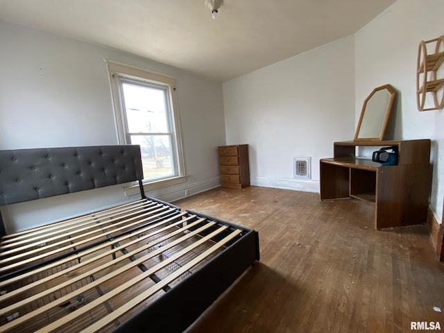bedroom with baseboards, visible vents, and hardwood / wood-style floors