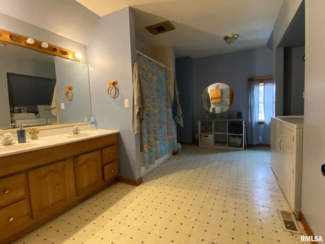 bathroom featuring double vanity, visible vents, a sink, tile patterned floors, and washer and dryer