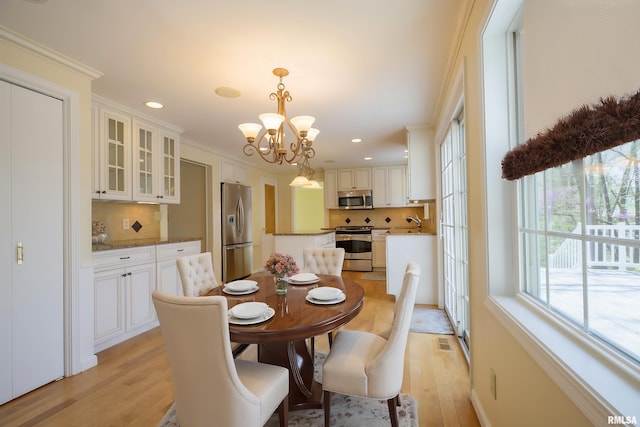 dining room featuring crown molding, visible vents, light wood-type flooring, recessed lighting, and a notable chandelier