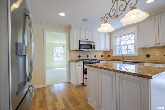 kitchen featuring light wood-style flooring, stainless steel appliances, white cabinets, ornamental molding, and backsplash