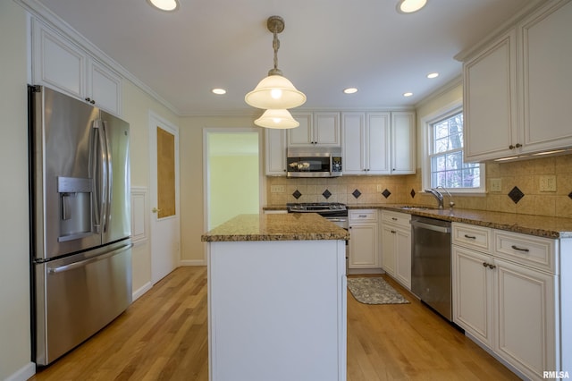 kitchen with light wood-style flooring, stainless steel appliances, a kitchen island, a sink, and stone countertops