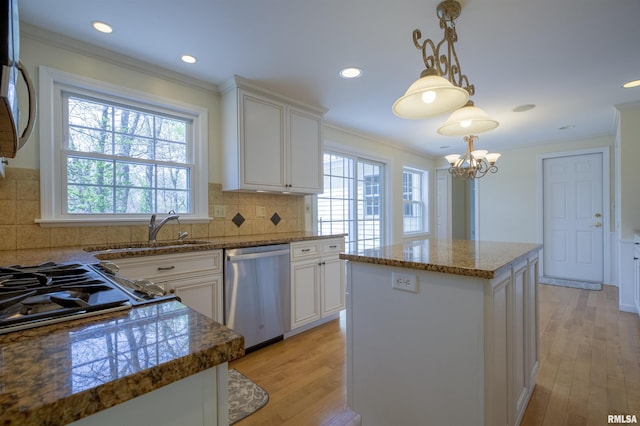 kitchen with stainless steel appliances, light wood finished floors, a kitchen island, and a sink
