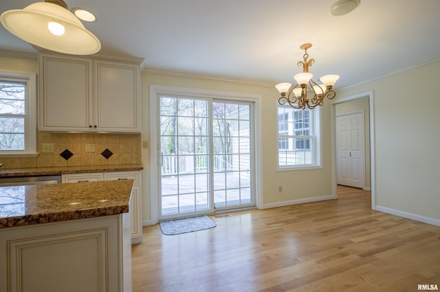 interior space featuring light wood finished floors, ornamental molding, and a notable chandelier