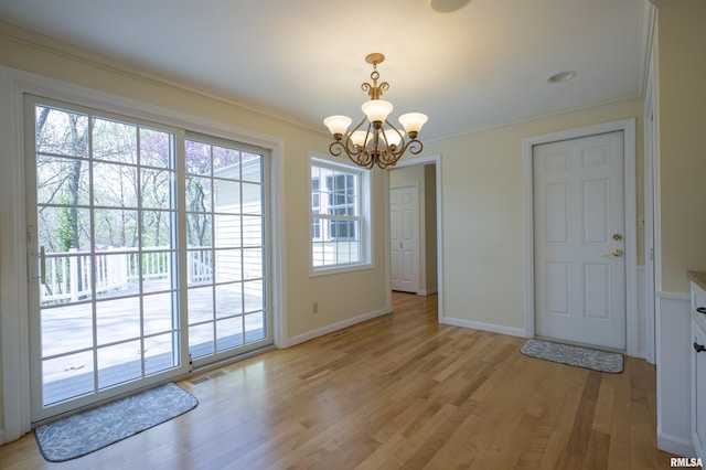 doorway to outside featuring an inviting chandelier, light wood-style flooring, ornamental molding, baseboards, and visible vents