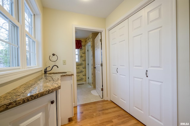 corridor featuring light wood-style floors and a sink