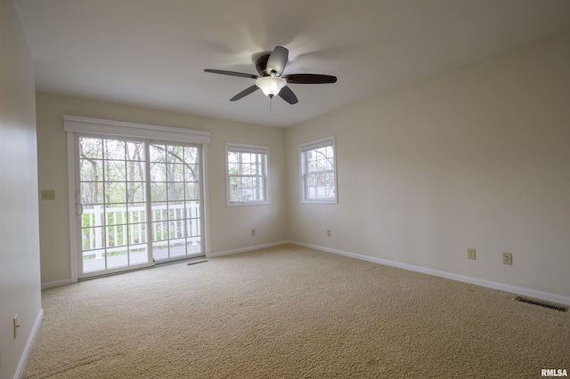 spare room with visible vents, a ceiling fan, baseboards, and light carpet