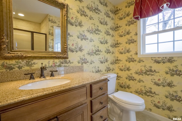 bathroom featuring toilet, vanity, wallpapered walls, and a stall shower