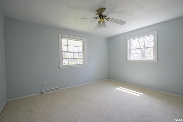 carpeted empty room featuring baseboards, visible vents, and ceiling fan