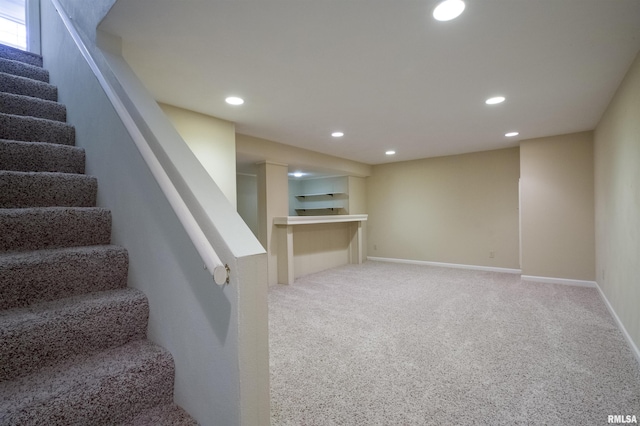 finished below grade area featuring light carpet, baseboards, recessed lighting, and stairs