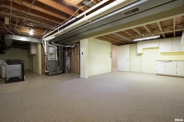 unfinished basement featuring water heater, visible vents, and heating unit