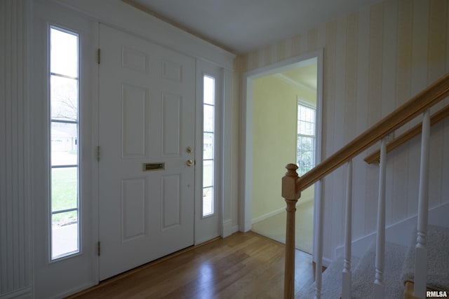 entryway with wallpapered walls, stairway, wood finished floors, and baseboards