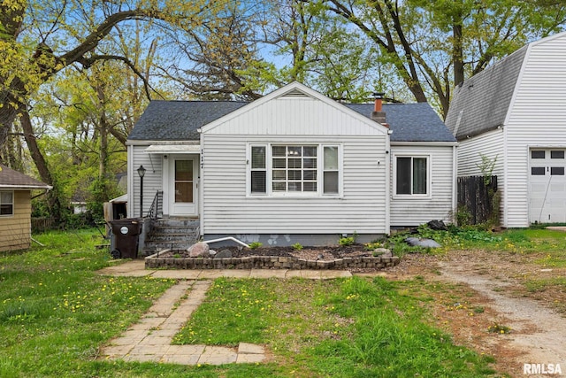 bungalow featuring roof with shingles, entry steps, and a front lawn