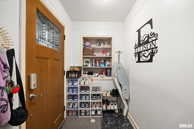 doorway with built in shelves, carpet flooring, and baseboards