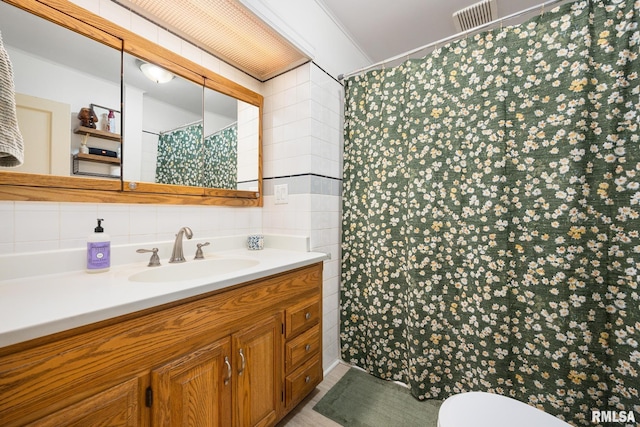 bathroom with a shower with shower curtain, toilet, ornamental molding, tile walls, and vanity