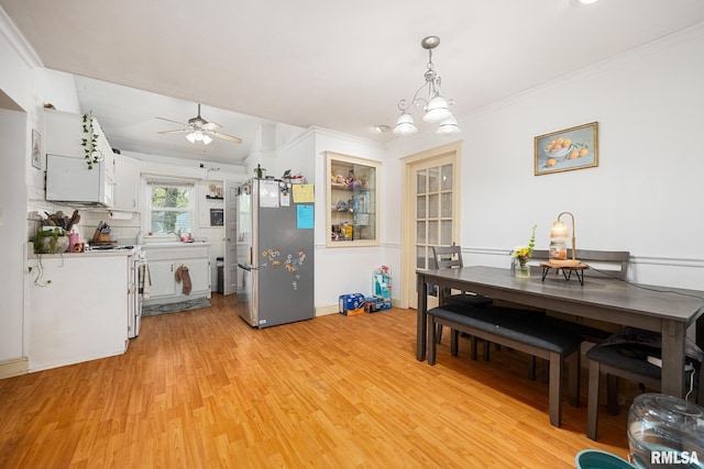 dining area featuring ornamental molding, light wood finished floors, and ceiling fan with notable chandelier