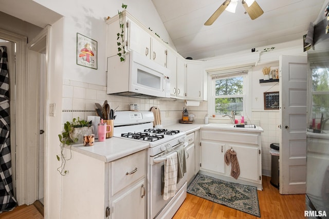 kitchen featuring light countertops, a sink, ceiling fan, and white appliances
