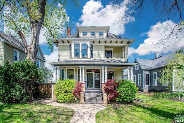 traditional style home with covered porch, fence, a chimney, and a front lawn