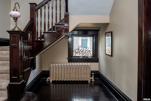 staircase featuring radiator heating unit, wood finished floors, and baseboards