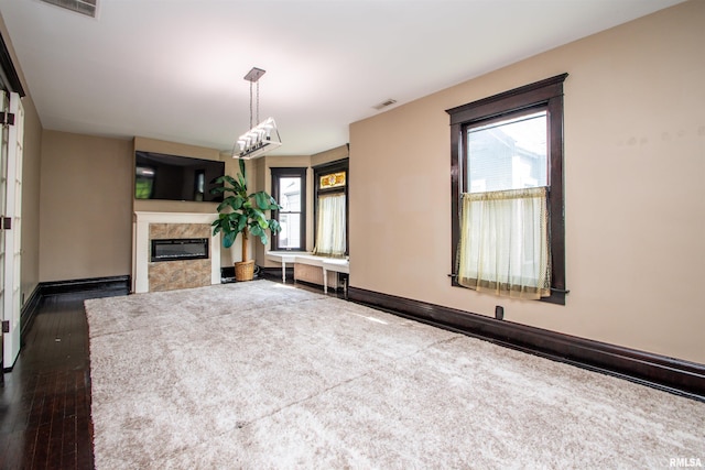 unfurnished living room featuring visible vents, a healthy amount of sunlight, a high end fireplace, and baseboards