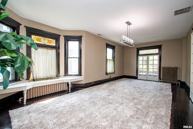 unfurnished room featuring radiator, visible vents, wood finished floors, and baseboards