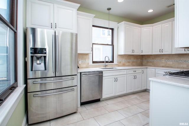 kitchen featuring appliances with stainless steel finishes, tasteful backsplash, white cabinets, and a sink