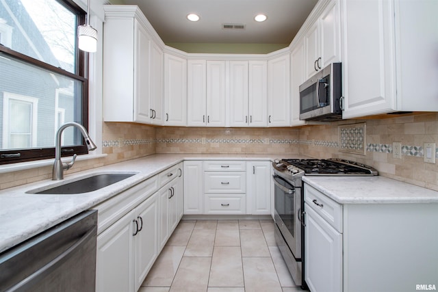 kitchen featuring white cabinets, a sink, visible vents, stainless steel appliances, and backsplash