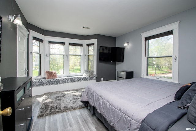 bedroom featuring wood finished floors, visible vents, and multiple windows