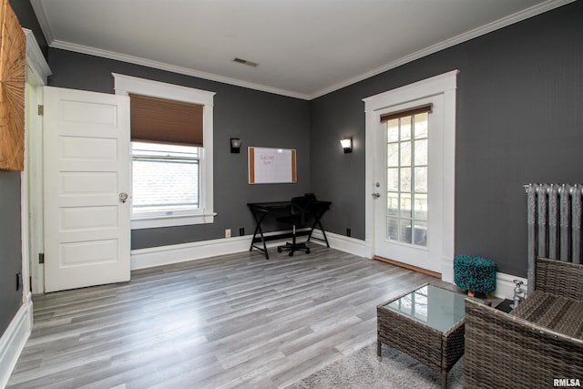 sitting room with wood finished floors, plenty of natural light, and crown molding