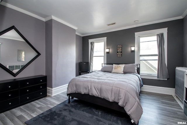 bedroom with baseboards, visible vents, wood finished floors, and multiple windows