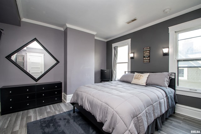 bedroom featuring baseboards, wood finished floors, multiple windows, and crown molding