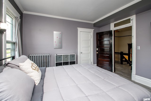 bedroom featuring wood finished floors, radiator, electric panel, baseboards, and crown molding