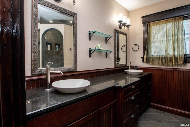 full bathroom featuring tile patterned flooring, a wainscoted wall, a sink, and double vanity