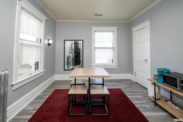 dining space with dark wood-style floors, visible vents, and crown molding